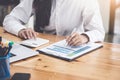 A businesswoman using pen point to chart document is researching earnings affected by the coronavirus pandemic to adjust