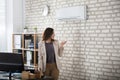 Businesswoman Using Remote Control Of Air Conditioner Royalty Free Stock Photo
