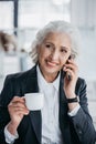 Businesswoman using smartphone and drinking coffee at workplace in office Royalty Free Stock Photo