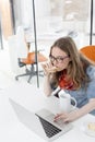 Businesswoman using touchpad of laptop while having breakfast in office Royalty Free Stock Photo