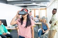 Businesswoman using virtual realty headset while diverse colleagues standing in background Royalty Free Stock Photo