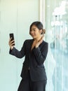 Businesswoman video calling with her foreign partner while standing in office room