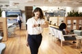 Businesswoman Walking Through Modern Office Checking Health Data On Smart Watch
