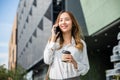 businesswoman walking outdoors talking on cell smart mobile phone and holding coffee cup takeaway Royalty Free Stock Photo