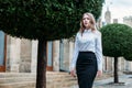 Businesswoman walks near the business center against background of green trees