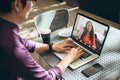 Businesswoman waving at asian businessman while video conferencing through laptop in office