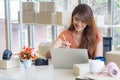 Businesswoman wearing casual cloth sitting in the office. The work desk in the office has a laptop, barcode reader prepare for