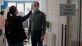 Businesswoman wearing face mask checking workers temperature