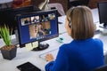 Businesswoman wearing headphones, sitting at desk using computer having video call Royalty Free Stock Photo