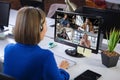 Businesswoman wearing headphones, sitting at desk using computer having video call Royalty Free Stock Photo