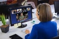 Businesswoman wearing headphones, sitting at desk using computer having video call Royalty Free Stock Photo