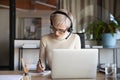 Businesswoman wearing headset writing notes, using laptop in office Royalty Free Stock Photo