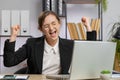 Businesswoman winner working browsing typing on laptop at office celebrate big lottery win good news Royalty Free Stock Photo