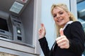 Businesswoman withdrawing money from credit card at ATM and showing okay sign