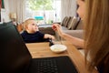 Businesswoman working at home and feeding baby Royalty Free Stock Photo