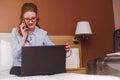 Businesswoman working in hotel room, using laptop and mobile phone Royalty Free Stock Photo