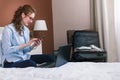 Businesswoman working in hotel room, using laptop and mobile phone Royalty Free Stock Photo