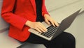 Businesswoman working with laptop in the city wearing red blazer jacket, woman's hands typing text on the keyboard pc Royalty Free Stock Photo