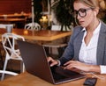 Businesswoman Working On Laptop In Coffee Shop. Young business woman uses laptop in cafe. Royalty Free Stock Photo