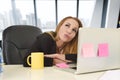 Businesswoman working at laptop computer sitting on the desk absent minded
