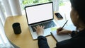 Businesswoman working on laptop computer and writing on agenda.