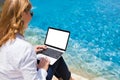 Businesswoman working on laptop on vacation by the pool