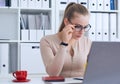 Young beauiful Caucasian businesswoman in glasses working on notebook computer and business document at office.