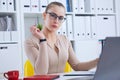 Young beauiful Caucasian businesswoman in glasses working on notebook computer and business document at office.