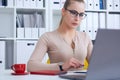 Young beauiful Caucasian businesswoman in glasses working on notebook computer and business document at office.