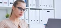 Young beauiful Caucasian businesswoman in glasses working on notebook computer and business document at office.