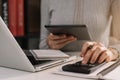 Businesswoman working with tablet and using a calculator to calculate the numbers of static in office. Royalty Free Stock Photo