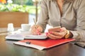 Businesswoman writing in notebook using smartphone, coffee break Royalty Free Stock Photo