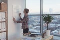 Businesswoman writing day plan on white magnet board, modern office. Side view of caucasian female employee planning Royalty Free Stock Photo