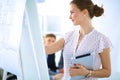 Businesswoman writing on flipchart while giving presentation to colleagues in office Royalty Free Stock Photo