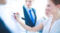 Businesswoman writing on flipchart while giving presentation to colleagues in office Royalty Free Stock Photo