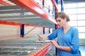 Businesswoman writing inventory on shelves in a warehouse