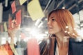 Businesswoman writing on sticky notes on glass wall while working in office Royalty Free Stock Photo