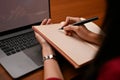 A businesswoman writing or taking notes something on her blank notebook at her office desk Royalty Free Stock Photo