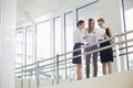 Businesswomen discussing over paperwork against railing