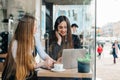 Businesswomen in formal wear are sitting in a cozy cafe and working with a laptop and talking.Beautiful two girls discussing Royalty Free Stock Photo