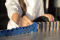 Businesswomen hand Stopping Falling wooden Dominoes effect from continuous toppled or risk Royalty Free Stock Photo