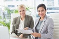 Businesswomen looking at camera and reading files Royalty Free Stock Photo