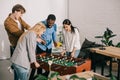 businesswomen playing table football and two male colleagues pointing