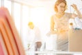 Businesswomen removing tangled cables from box at desk in new office with yellow lens flare in background Royalty Free Stock Photo