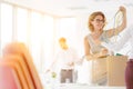 Businesswomen removing tangled cables from box at new office with yellow lens flare in background