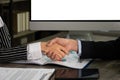 Businesswoman shaking hands with businessman partner after successfully business contract agreement while sitting at office desk