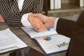 Businesswomen seated at office desk shaking hands with businessman after signed contract