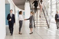 Businesswomen shaking hands in a busy modern lobby Royalty Free Stock Photo