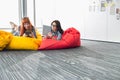 Businesswomen using digital tablets while relaxing on beanbag chairs in creative office Royalty Free Stock Photo