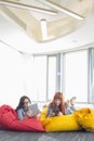 Businesswomen using digital tablets while relaxing on beanbag chairs in creative work space Royalty Free Stock Photo